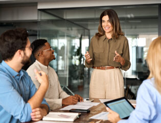 happy middle aged business woman leader working with diverse team at meeting.
