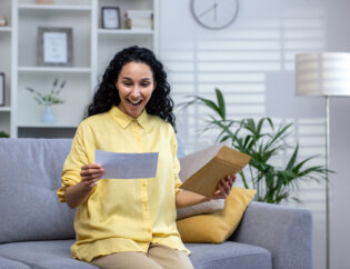 joyful and happy woman at home received mail envelope with notification, hispanic woman reading good news on paper and happy sitting on sofa in living room