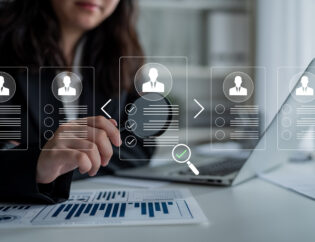 professional businesswoman reviewing resumes and analyzing data in modern office environment with graphs and charts displayed on a laptop screen. glyphic