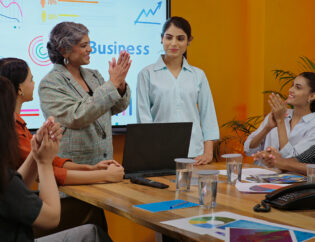indian happy senior boss woman project manager young adult expert girl lady get work indoor job office asian smiling proud leader talk hiring new intern staff join group team clap hands at place